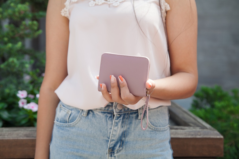Woman standing on the street holding wallet.